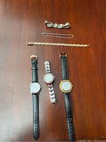 Overview of three wristwatches and three bracelets on wood surface