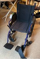 Front view showing blue frame, black seat and back upholstery, footrests deployed