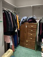 Overall view of clothing on racks with wooden chest and folded garments