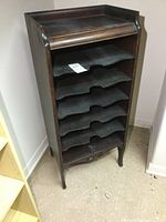 Front angle view of antique wooden sheet music cabinet with six shelves and curved edges on each shelf.