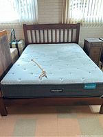 Full view of queen-sized wooden bed frame with Beautyrest Harmony mattress on top.