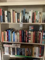 Full view of three shelves with hardcover and paperback books, mixed fiction and non-fiction.