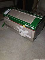 Box showing Hampton Bay 30-inch ceiling fan with light in green and gray packaging.