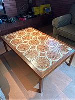 Full view of the rectangular coffee table with 12 decorative tiles on top and wooden legs in a living room setting.