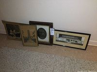 Lot of four older framed pictures lined up on the floor showing various sizes and frames with worn condition and missing trim