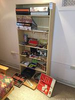 Wooden shelf unit with various older board games and several photo albums visible on and inside shelves