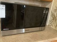 Front view of Panasonic Inverter microwave model NN-ST6965 showing stainless steel and black glass design.