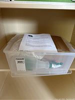 Photo of transparent plastic bin with lid containing spray bottle, packaging, and instructions for mushroom growing.
