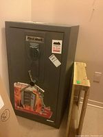 Front three-quarter view of grey First Alert safe on wooden platform