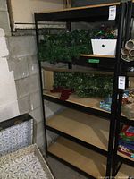 Metal shelving unit in corner with particleboard shelves and black metal frame.