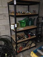 Front-side view of the metal shelving unit with tools and garden items on shelves showing structure and shelf material.