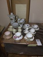 Full collection of teacups, saucers, coffee pot, and espresso set arranged on wooden table