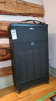 Front view of the RespirAide 300T black electronic air purifier, showing the grille and wheels.