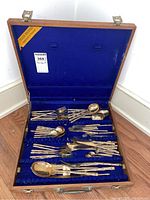 Overview of open wooden canteen showing entire bronze flatware set arranged on blue velvet lining