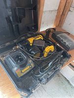 Dewalt drill, charger, battery, and carrying case in a wooden shed or garage setting.