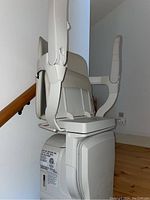 Side view of stairlift chair and curved rail mounted on straight wooden staircase