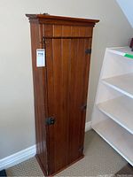 Full view of antique pine firearm cabinet showing vertical panel door, metal hinges, and lock mechanism.