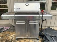 Front view of Weber Genesis grill with closed lid, side shelves and cabinet storage