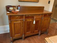 Full front view of buffet sideboard showing three drawers above three paneled doors with turned column accents