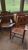Two matching wooden armchairs, left stationary and right rocking, positioned in front of window.