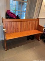 Full view of wooden pew showing slatted back, seat and one carved end
