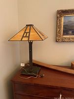 Full view of table lamp on wooden surface, showing shade, stem, base, and cord