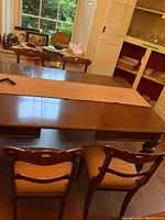 View of dining table and four matching wooden dining chairs with orange fabric seats.