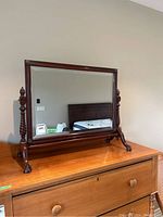 Front view of the wooden dresser mirror showing the beveled glass and carved posts.