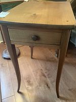 Front view of the solid wood end table showing the drawer and curved legs