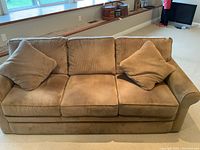 Front view of three-seat corduroy sofa with two matching accent pillows