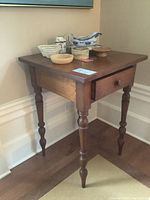 Side view of the solid wood square side table showing surface with various small decorative items on top.