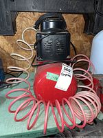 Jobmate 3-gallon air compressor with attached coiled air hose on green workbench.