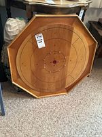 Octagonal wood crokinole board with natural wood finish and playing surface viewed from the front.