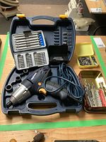 Impact driver and assorted bits in molded plastic case, showing cord and trigger.