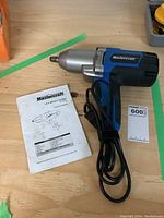 Mastercraft 3.5A impact driver on wood surface next to instruction manual and numbered lot tag.