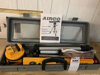 Airco laser level kit inside gray plastic carrying case including laser level, tripod, safety glasses, and user manual.