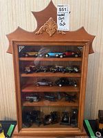 Wooden display case with glass front filled with model cars and miniatures