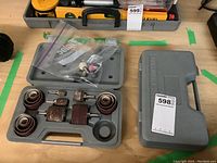 Two gray plastic cases with sanding drums and sanding sleeves on a workbench