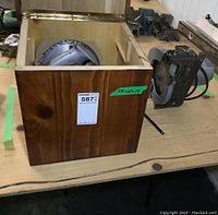 Wooden box open showing circular saw blades inside, Skil saw motor and body placed beside it on a wooden table.