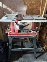 Front view of Skilsaw 10 inch table saw on metal stand in garage environment.