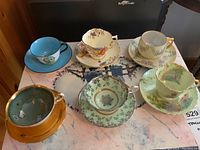 Overhead photo of all six teacups with matching saucers showing colors and designs.