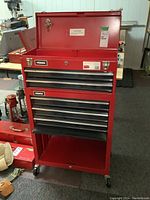 Front view of red Homak rolling tool cabinet showing top chest, drawers, open base and casters