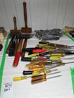 Photo showing assortment of hand tools spread on table including hammers, mallets, screwdrivers and wrenches.