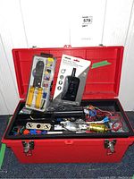 Red toolbox open showing contents including crimping pliers, inline water valve indicator, wiring, and electrical components