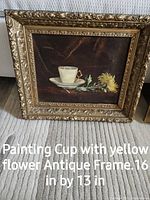 Photo of antique painting showing white cup and yellow flower in ornate gold frame, 16 by 13 inches