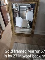 Gold framed rectangular mirror 37 by 27 inches with wood backing shown leaning against wall