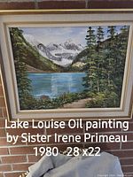 Framed oil painting of Lake Louise by Sister Irene Primeau, dated 1980, depicting a mountain lake view with trees and snow-capped peaks in a 28 x 22 inch format.