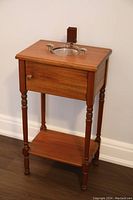 Full view of the antique wooden smoker stand showing its turned legs, a small shelf at the bottom, and the refinished wood surface.