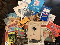 Photo showing a variety of vintage paper items including Ice Capades booklet and various brochures and photographs on a wooden table.