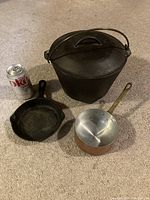 Full set arranged by size next to a soda can for scale: an 11-inch cast iron pot with lid, small cast iron fry pan, small copper pot with long handle.